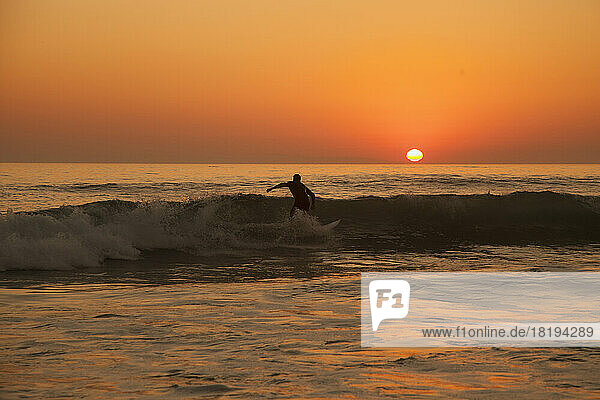Man surfing at Laguna beach during sunset