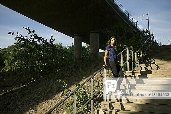 Young woman leaning on railing of steps