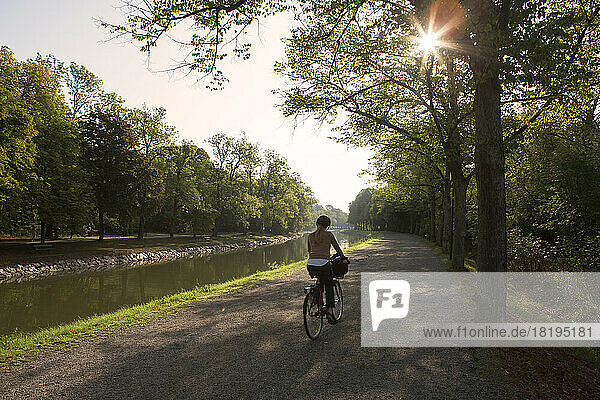 Woman riding bicycle on path through park