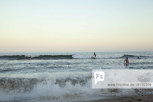 People surfing on sea at sunset