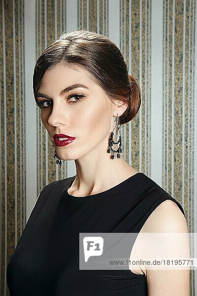 Porträt einer wunderschönen Dame mit elegantem Abend-Make-up  roten Lippen und Ohrringen