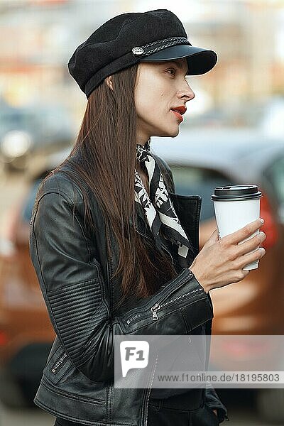 Attractive girl walking along the street with cup of coffee