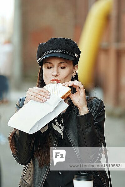 Attractive girl eating sandwich on the street
