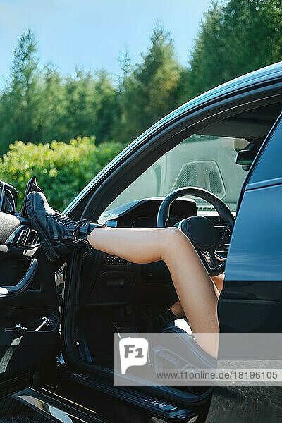 Sexy Frauenbein in rauem Stiefel ruht auf einer Autotür