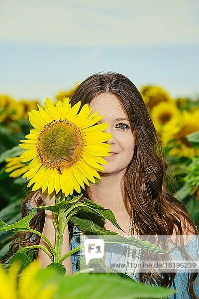Schöne junge Frau  die die Hälfte ihres Gesichts mit einer Sonnenblume verdeckt