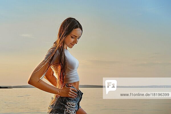 Positive junge Frau genießt frische Brise bei Sonnenuntergang