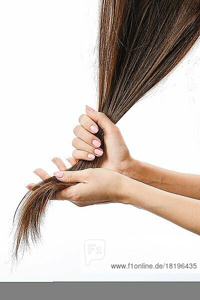 Weibliche Hände halten sprödes beschädigtes Haar. Haarpflege Problem Konzept