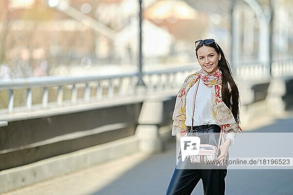 Fröhliche junge Frau geht auf der Brücke in sonnigen Tag