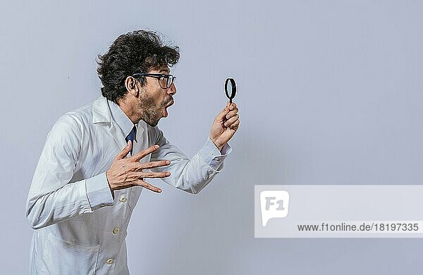 Wissenschaftler  der ein Vergrößerungsglas hält und zur Seite schaut  Mann im weißen Kittel mit einem Vergrößerungsglas  der Werbung betrachtet  Überrumpelter Wissenschaftler  der mit einem Vergrößerungsglas zur Seite schaut