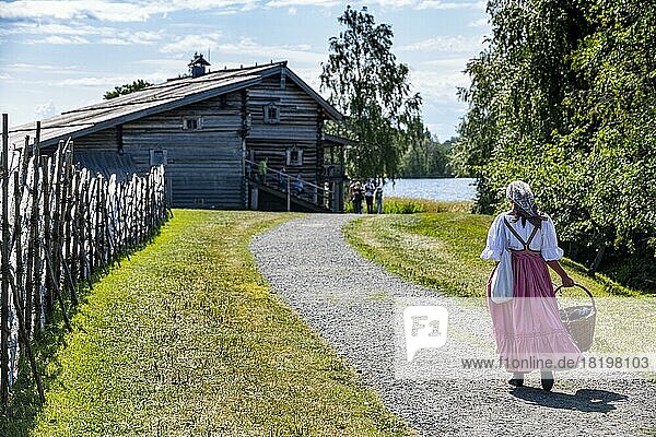 Traditionell gekleidete Frau auf dem Weg zu einem Holzhaus  Unesco-Stätte Insel Kizhi  Karelien  Russland  Europa