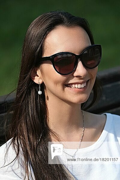 Outdoor portrait of beautiful smiling girl in big sunglasses