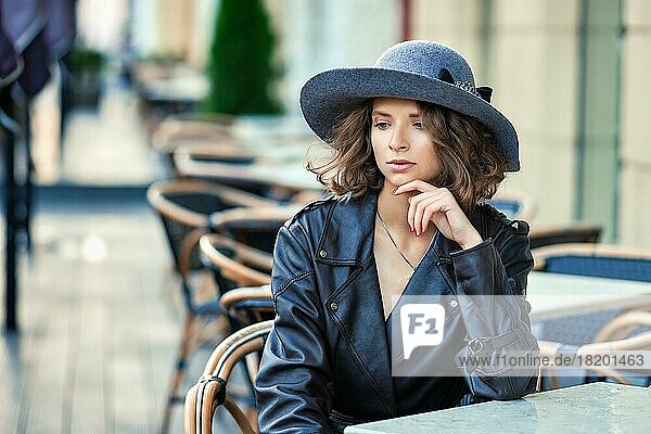 Outdoor-Foto von stilvollen Frau trägt altmodische Mantel  mit Pause in der Straße im Freien Café