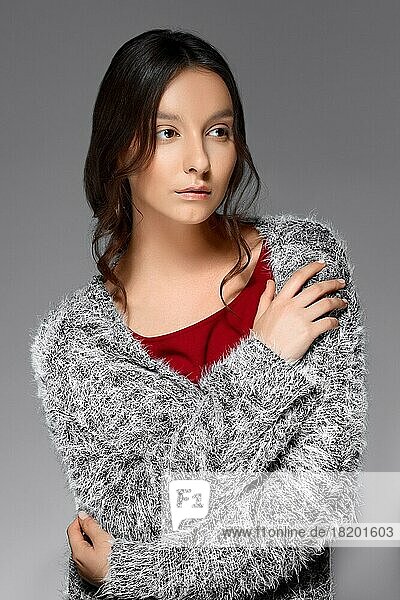 Porträt eines zarten Mädchens mit glattem Haar  eingewickelt in einen flauschigen Pullover