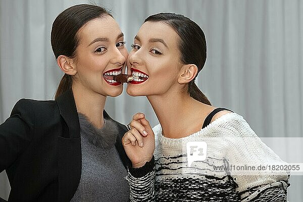 Zwei junge Mädchen essen ein Bonbon von Mund zu Mund