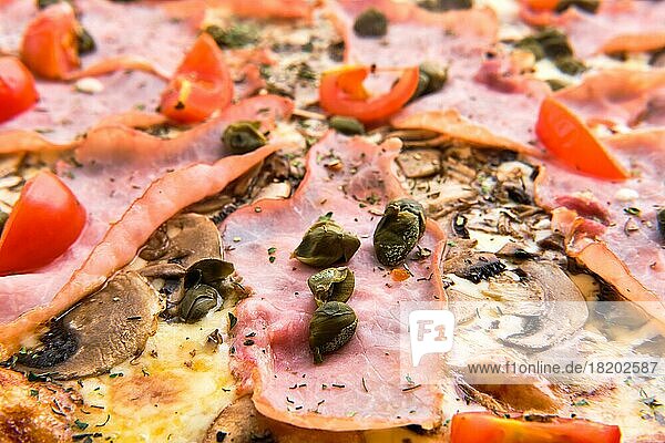Makroaufnahme von Tomate  Schinken  Sardellen und Käse auf Pizza (Foto mit geringer Schärfentiefe)