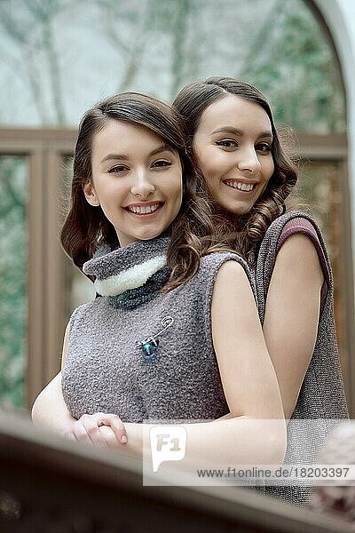Zwei Schwestern im ärmellosen Kleid aus warmer Wolle umarmen sich gegenseitig