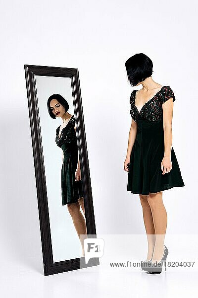Mädchen  das ein kurzes Kleid anprobiert und sich im Spiegel betrachtet