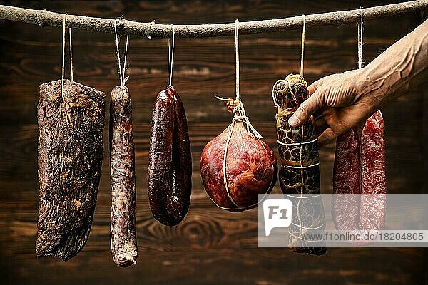 Sortiment getrockneter Fleisch- und Wurstwaren  die auf einem Stock in einer Scheune hängen
