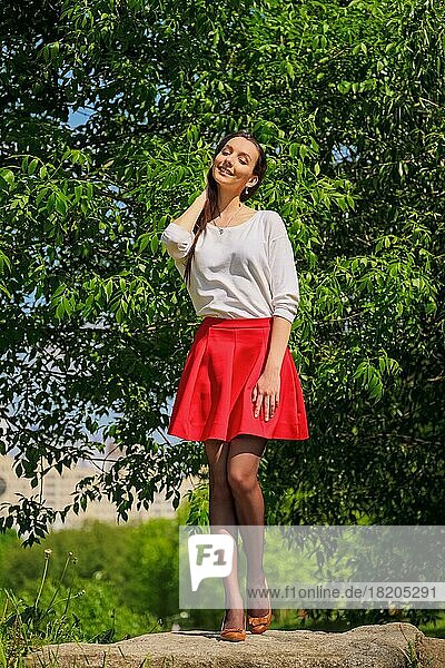 Portrait of a girl in red skirt and white blouse standing on river bank