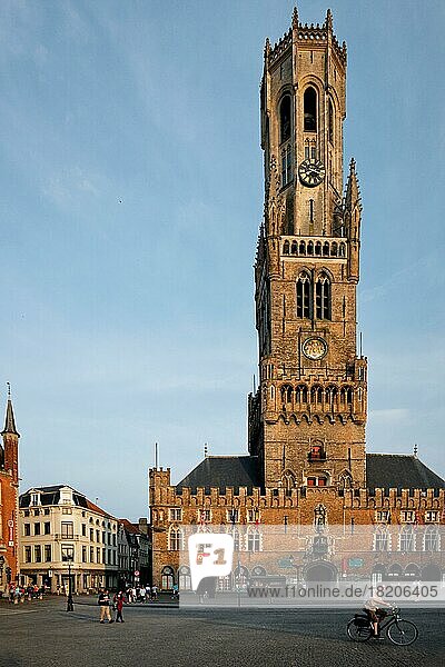 BRÜGGE  BELGIEN  28. MAI 2018: Belfried Turm berühmtes Touristenziel und Grote Markt Platz in Brügge  Belgien mit Fußgängern und Fahrrad bei Sonnenuntergang
