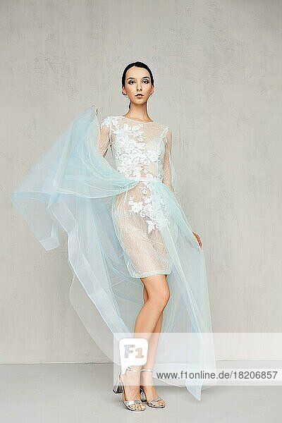 Beautiful young woman tossing the hem of the transparent tulle dress up