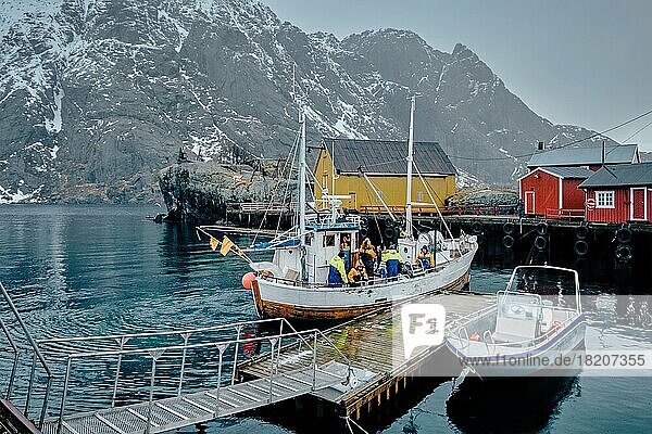NUSFJORD  NORWAY  MARCH 25  2017: Fishermen and fishing boat on pier in Nusfjord fishing village  Lofoten islands  Norway  Europe