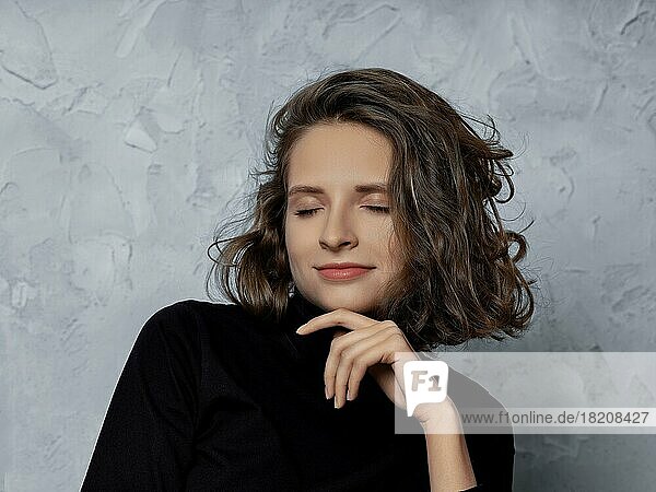 Pensive young woman with curly hair and closed eyes