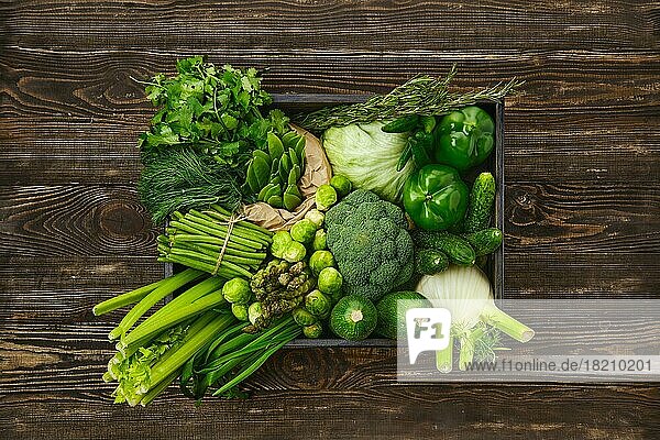 Verschiedene frische grüne Gemüse in Holzkiste auf Holz Hintergrund