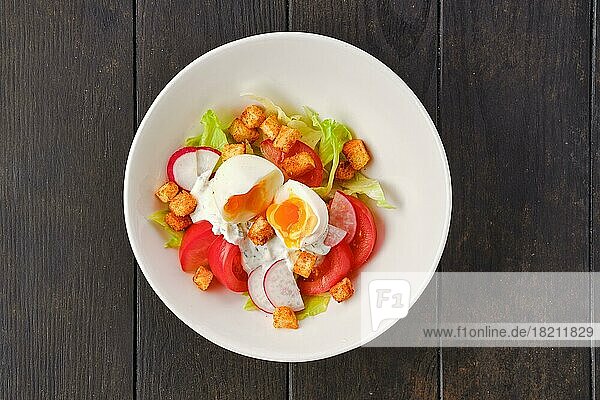 Draufsicht auf Salat mit frischer Tomate  Radieschen  gekochtem Ei und Crouton auf dunklem Holztisch