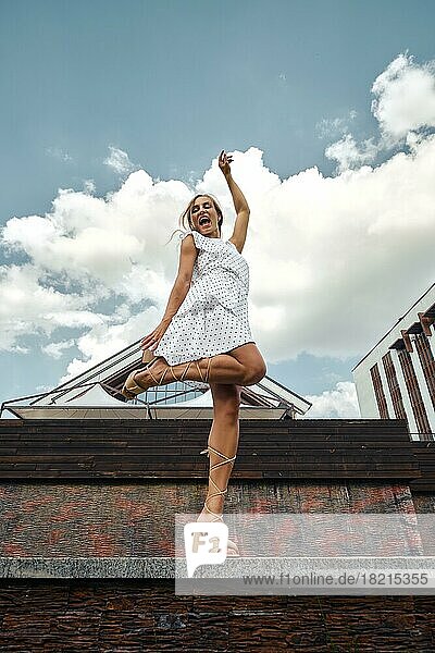 Junge fröhliche Frau verbringt Zeit mit Tanzen an einem sonnigen Tag in einem Stadtpark