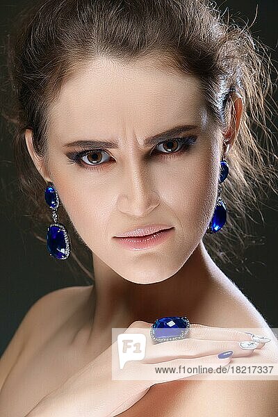 Porträt eines schönen Modemodells mit Bijouterie. Ohrringe  Fingerring und Halskette mit großen Kristallen. Frische Haut und natürliches Make-up
