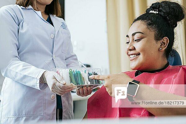 Dental patient choosing dental braces  Patient with dentist choosing colored rubber band. Patient with dentist choosing dental braces