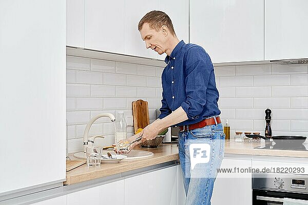 Ein Mann mittleren Alters wäscht nach dem Kochen zu Hause das Geschirr ab