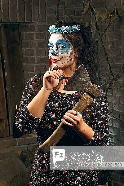 Young woman with axe and sugar skull makeup during Halloween. Face painting art