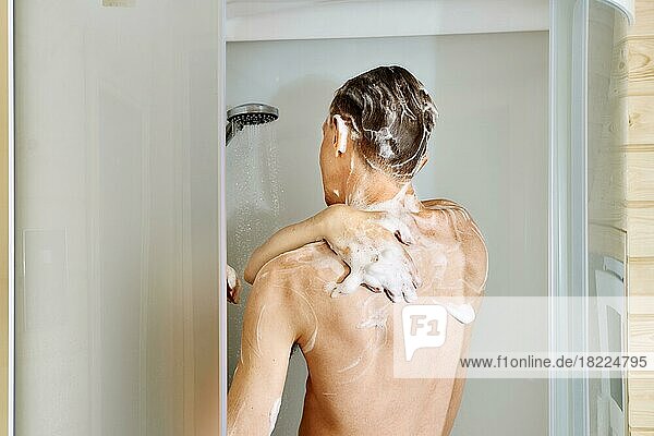 Rückansicht eines Mannes beim Duschen in der Kabine