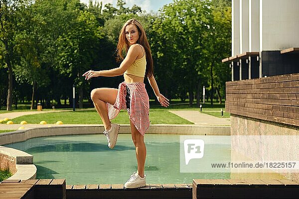 Junge fröhliche Frau tanzt auf Holzboden in der Nähe des öffentlichen Schwimmbads