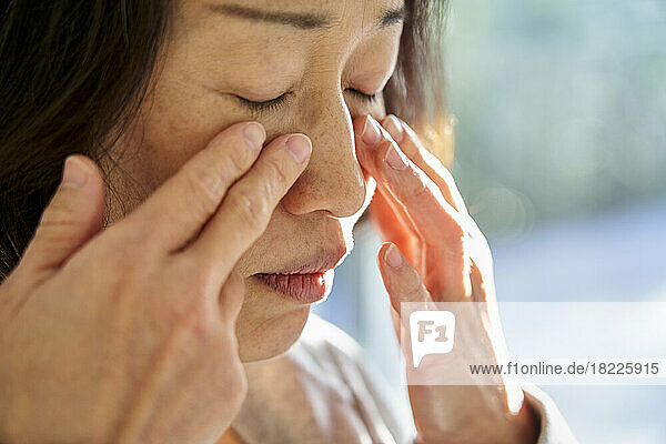 Close-up of senior Asian woman touching her face
