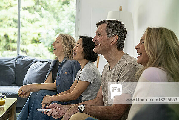 Diverse group of senior friends watching TV at linving room