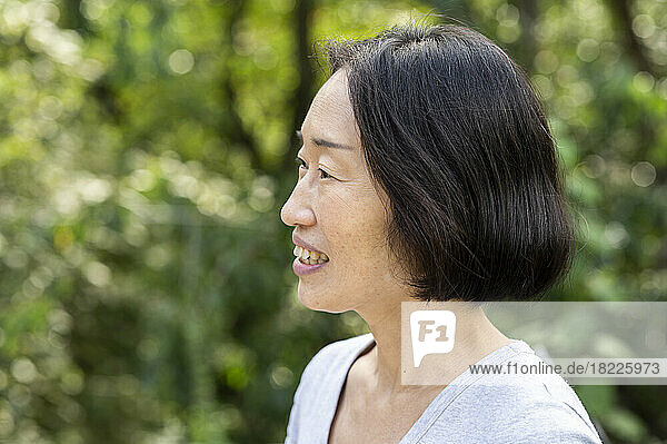 Side view shot of senior Asian-American woman standing outdoors