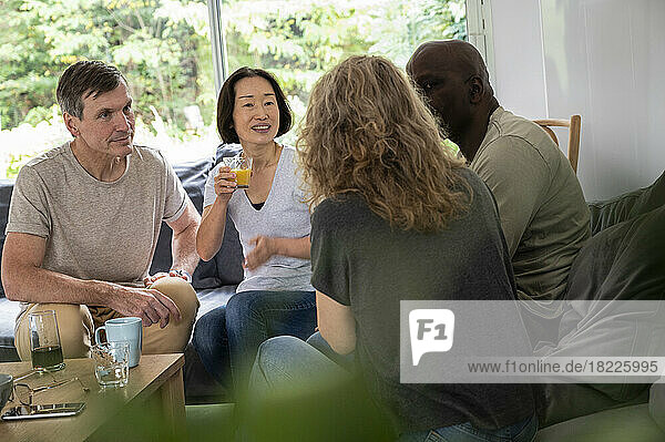 Group of diverse male and female friends sitting in living room enjoying their conversation