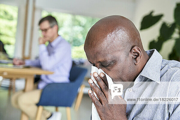 Close-up shot of senior African-American man with a cold blowing his nose
