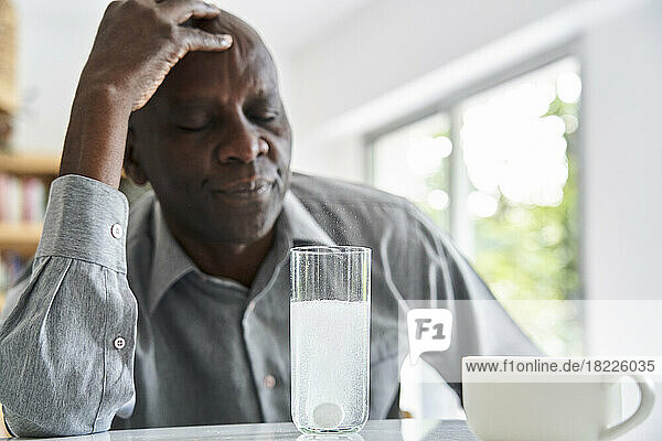Middle-aged African-American man with headache taking his medicine
