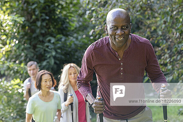 Senior African-American man holding hiking poles going for a hike with group of diverse senior friends
