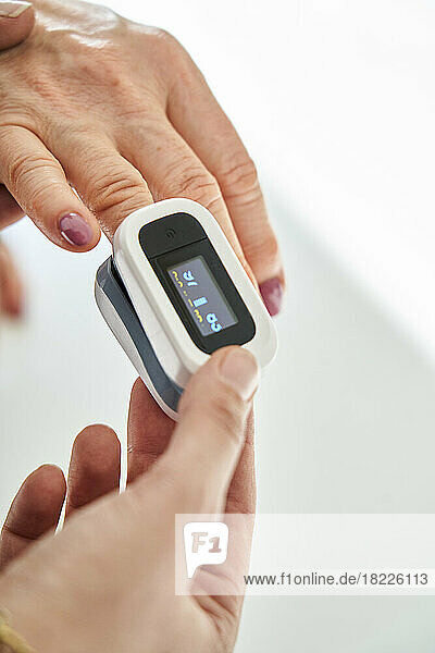 Woman measuring oxygen saturation with an oximeter