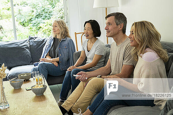 Diverse group of friends sitting on couch watching TV