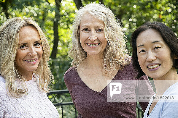 Portrait of three middle aged lady friends looking at camera while having a good time together outdoors