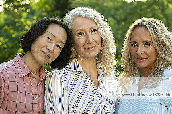 Group of three middle-aged women posing for photo in backyard
