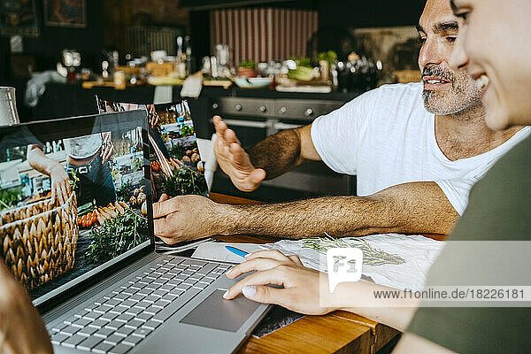 Food-Stylisten betrachten ein Foto auf dem Laptop  während sie im Studio zusammenarbeiten