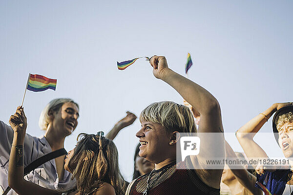 Glückliche nicht-binäre Person mit Freunden bei der Parade für LGBTQIA-Rechte