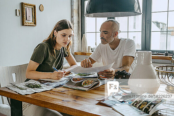 Business colleagues reviewing photograph while working at table in studio